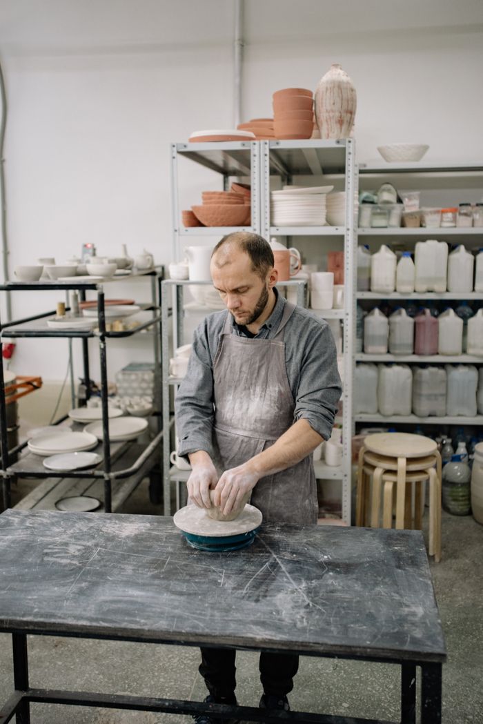 A potter shaping a vessel at the wheel